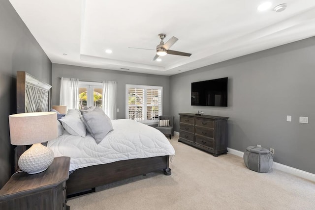 carpeted bedroom featuring access to exterior, a tray ceiling, french doors, and ceiling fan