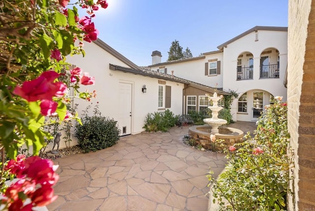 back of property with a balcony and a patio