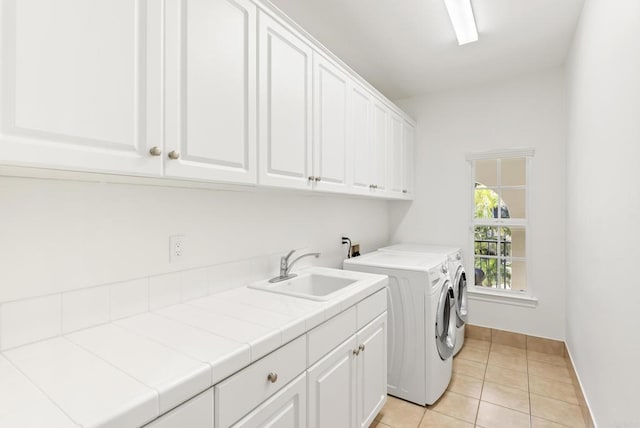 washroom featuring cabinets, sink, washing machine and dryer, and light tile patterned floors