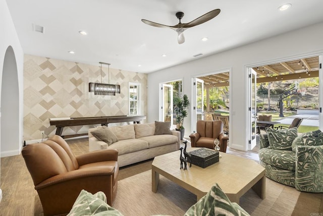 living room featuring tile walls, ceiling fan, and light hardwood / wood-style flooring