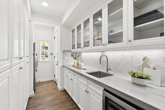 kitchen featuring sink, backsplash, dark hardwood / wood-style floors, light stone countertops, and white cabinets