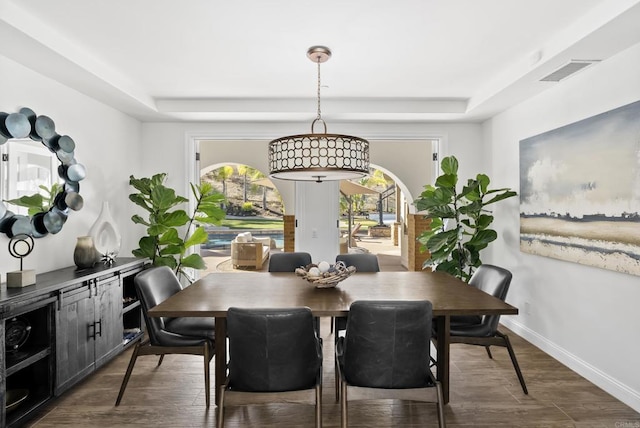 dining room featuring dark wood-type flooring and a raised ceiling