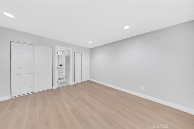 unfurnished bedroom with two closets and light hardwood / wood-style flooring