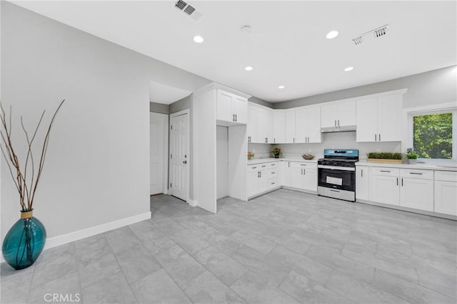 kitchen featuring gas range and white cabinetry