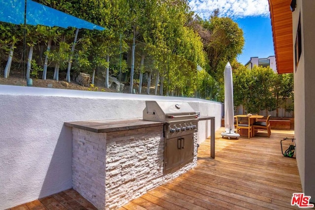 wooden terrace featuring area for grilling and an outdoor kitchen