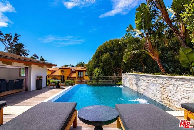 view of swimming pool featuring pool water feature and a wooden deck