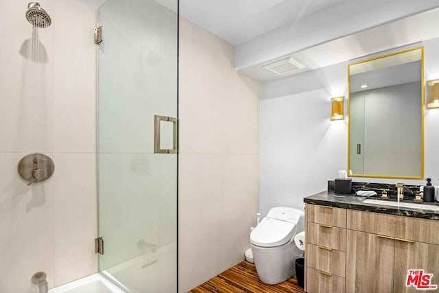 bathroom with vanity, hardwood / wood-style flooring, a shower with shower door, and toilet