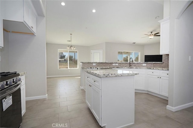 kitchen featuring hanging light fixtures, gas stove, white cabinets, and a center island