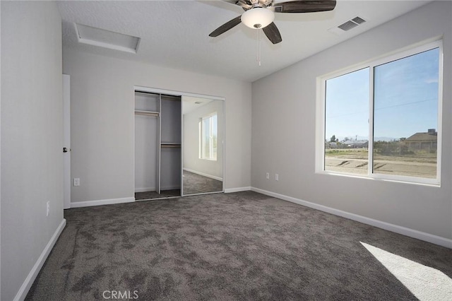 unfurnished bedroom with multiple windows, dark carpet, a closet, and ceiling fan