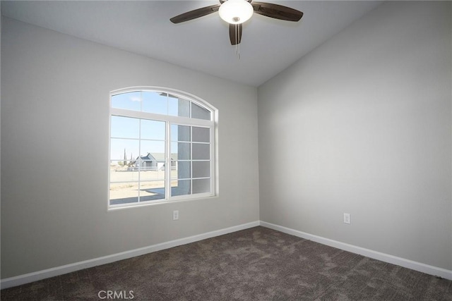 spare room featuring ceiling fan, lofted ceiling, a healthy amount of sunlight, and dark colored carpet