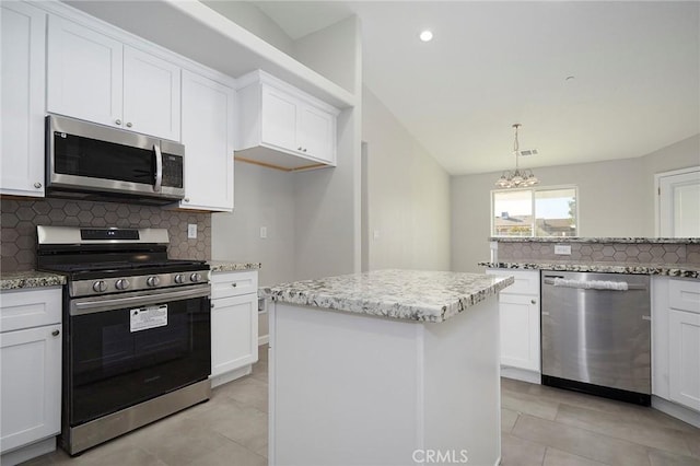 kitchen featuring stainless steel appliances, a center island, white cabinets, and decorative light fixtures