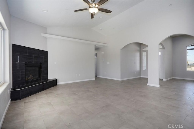 unfurnished living room featuring ceiling fan, a tiled fireplace, and vaulted ceiling