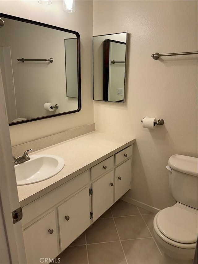 bathroom featuring toilet, tile patterned flooring, baseboards, and vanity