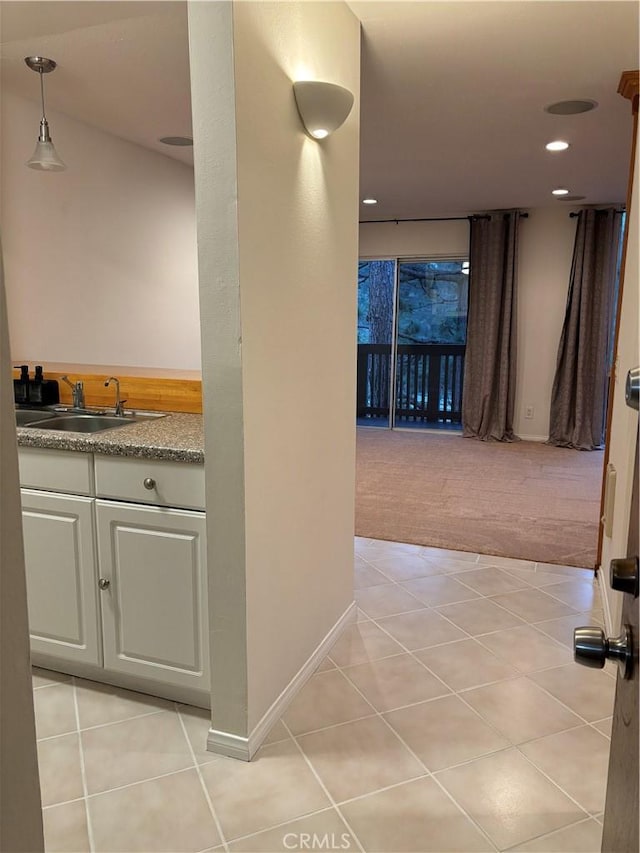 corridor with light tile patterned floors, recessed lighting, light colored carpet, a sink, and baseboards