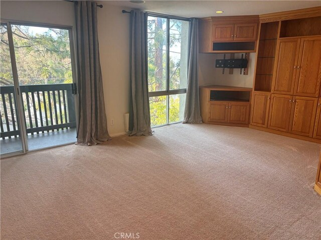 unfurnished living room featuring light colored carpet and plenty of natural light