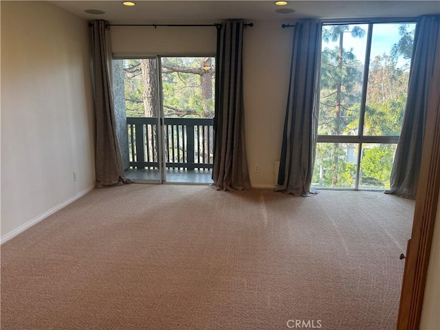 carpeted spare room featuring a wealth of natural light and baseboards