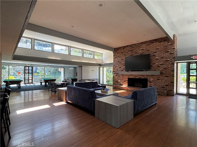 living room featuring dark wood-type flooring, billiards, brick wall, a brick fireplace, and french doors