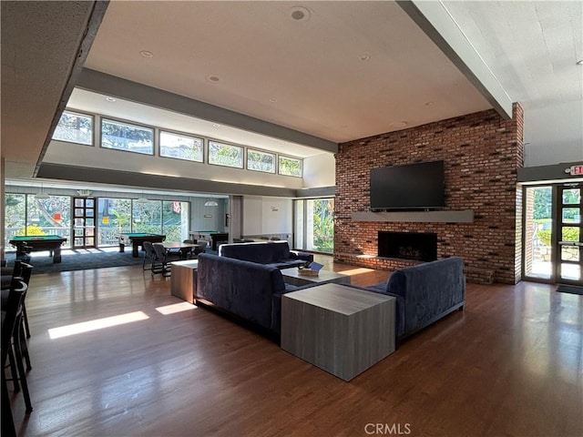 living room featuring a brick fireplace, french doors, wood finished floors, and pool table