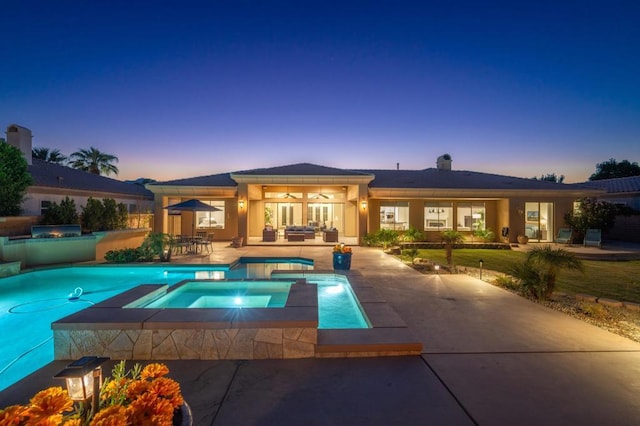 pool at dusk featuring an in ground hot tub, ceiling fan, and a patio