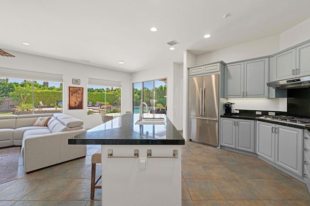 kitchen with gray cabinets, appliances with stainless steel finishes, sink, and a center island with sink