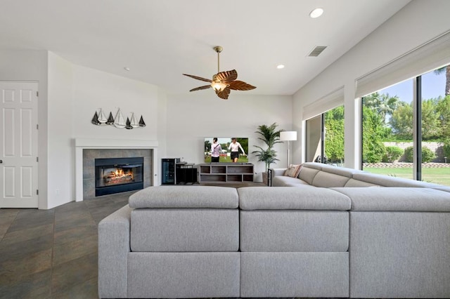 living room with a tile fireplace, a healthy amount of sunlight, and ceiling fan