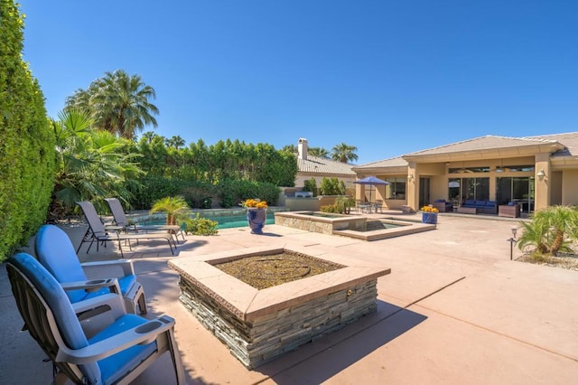 view of patio / terrace with a swimming pool with hot tub and an outdoor living space with a fire pit