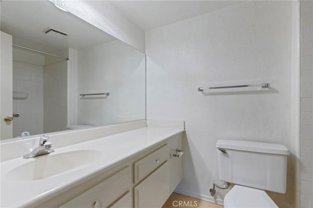 bathroom featuring toilet, vanity, and visible vents