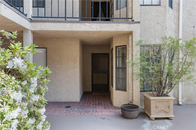 property entrance with a balcony and stucco siding