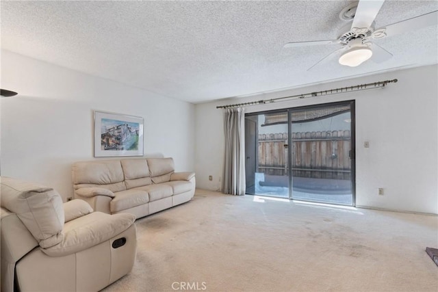 living room featuring light carpet, ceiling fan, and a textured ceiling