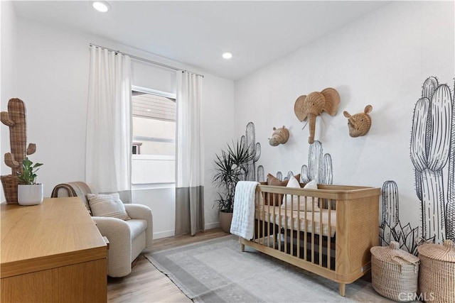 bedroom featuring a nursery area and light hardwood / wood-style floors