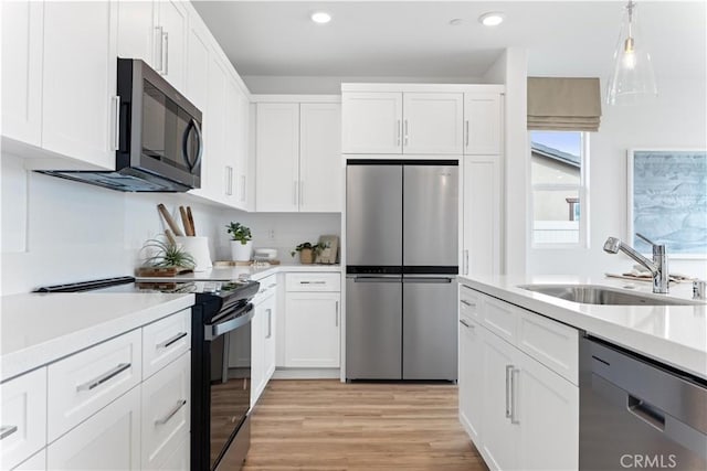 kitchen featuring hanging light fixtures, white cabinetry, sink, and black appliances