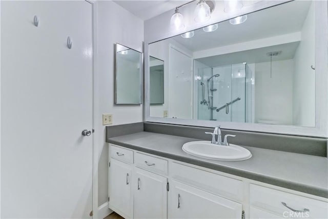 bathroom featuring a shower with door and vanity