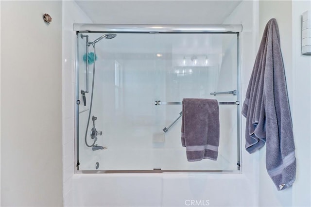 bathroom featuring combined bath / shower with glass door