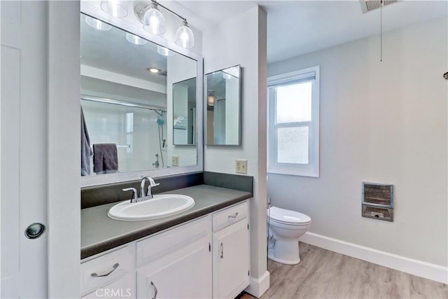 bathroom with heating unit, hardwood / wood-style floors, vanity, an enclosed shower, and toilet