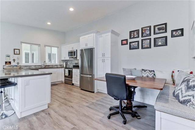 kitchen with white cabinetry, stainless steel appliances, sink, and light wood-type flooring