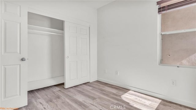 unfurnished bedroom featuring a closet, baseboards, and light wood finished floors