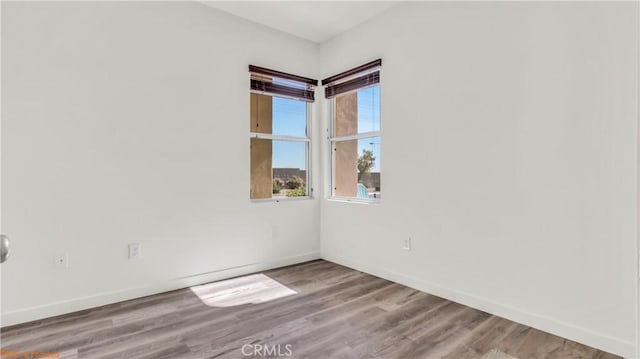 unfurnished room with light wood-type flooring and baseboards