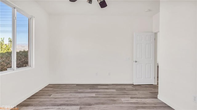 unfurnished room with light wood finished floors, a ceiling fan, and baseboards