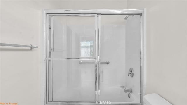 bathroom with a shower with shower door and toilet