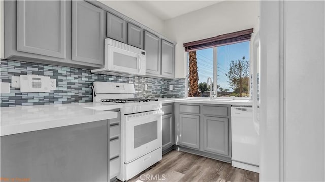 kitchen with gray cabinets, white appliances, a sink, and tasteful backsplash