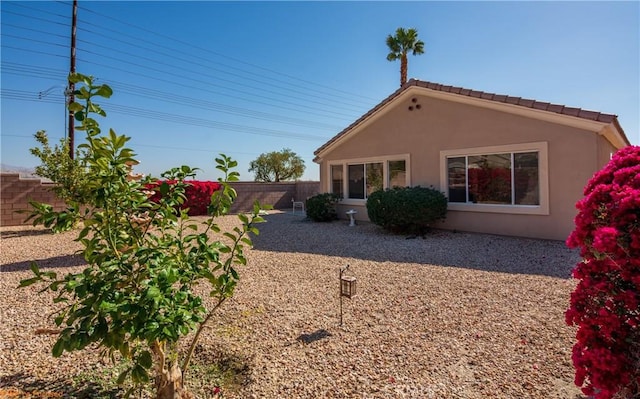 back of house with a fenced backyard and stucco siding