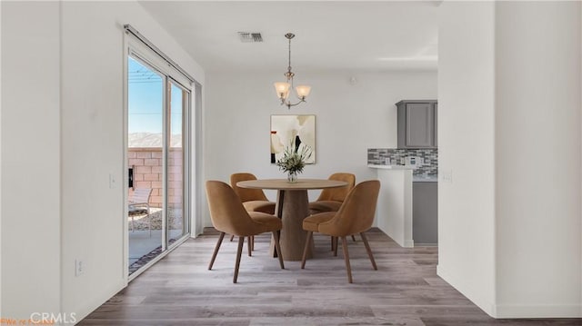 dining room featuring baseboards, visible vents, an inviting chandelier, and wood finished floors