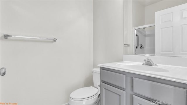 full bathroom featuring a shower with shower door, vanity, and toilet