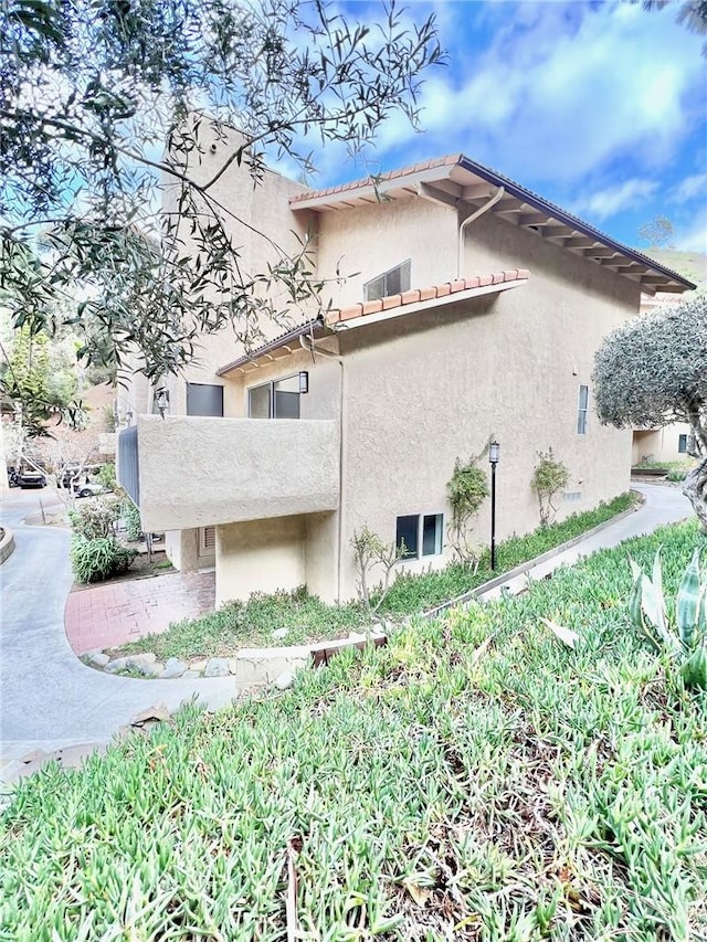 view of side of home with a tile roof and stucco siding