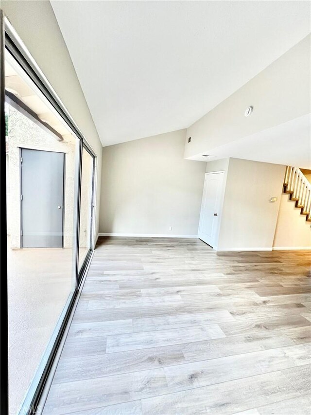 unfurnished room featuring lofted ceiling and light hardwood / wood-style floors