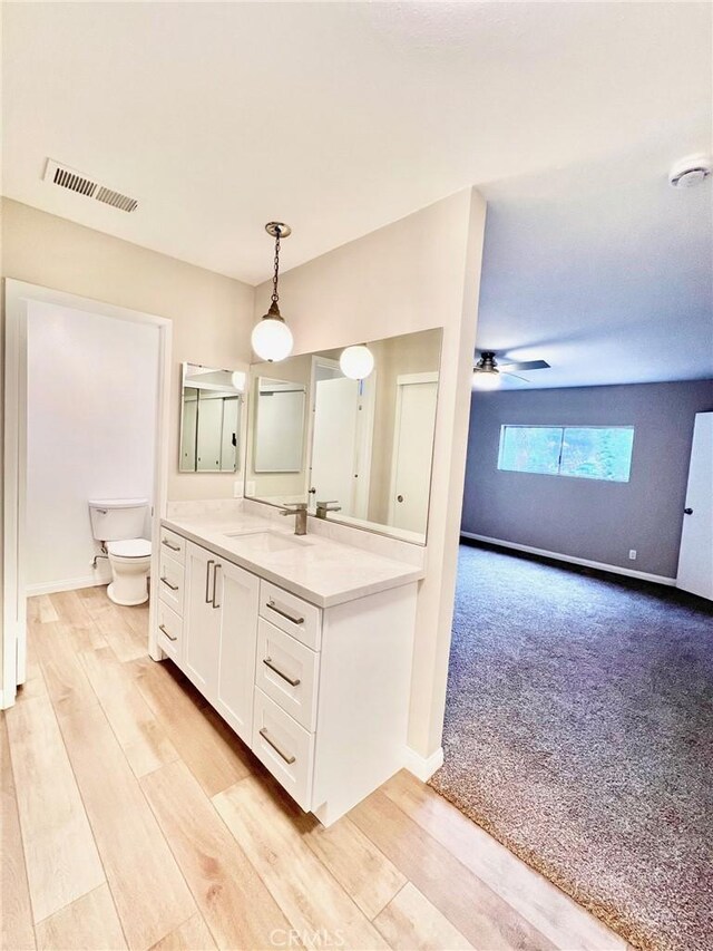 bathroom with hardwood / wood-style flooring, ceiling fan, vanity, and toilet