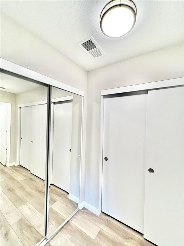 unfurnished bedroom featuring multiple closets and light wood-type flooring