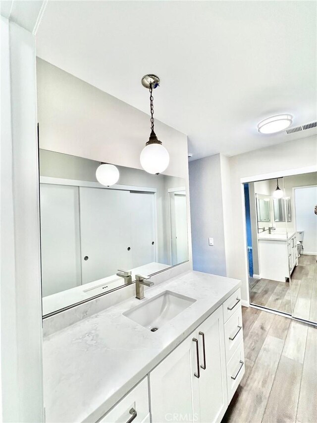 kitchen with light wood-type flooring, light stone countertops, sink, and white cabinets