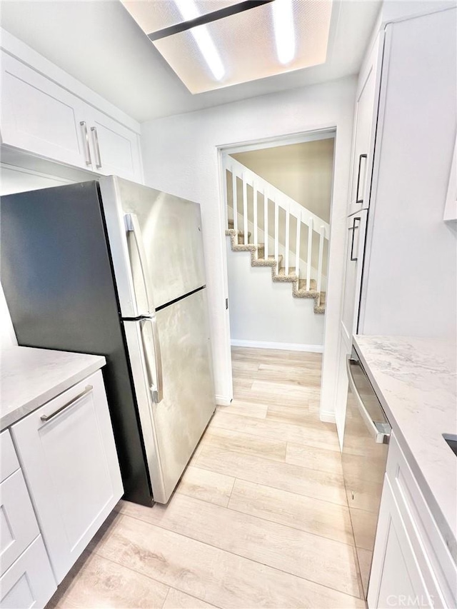 64 Avalon Terrace Rd, Avalon, CA 90704 - kitchen featuring light stone counters, baseboards, white cabinets, light wood-style floors, and appliances with stainless steel finishes