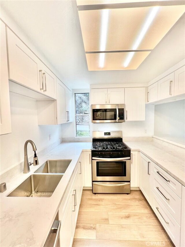 kitchen featuring white cabinetry, sink, light stone counters, and stainless steel appliances